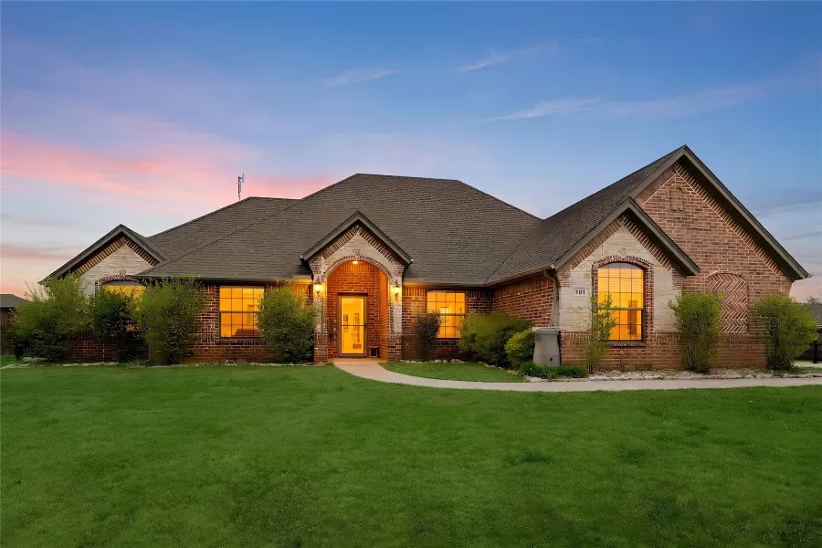 French country inspired facade with brick siding, a front yard, and a shingled roof