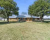 Ranch-style home with a front yard, a metal roof, brick siding, and covered porch