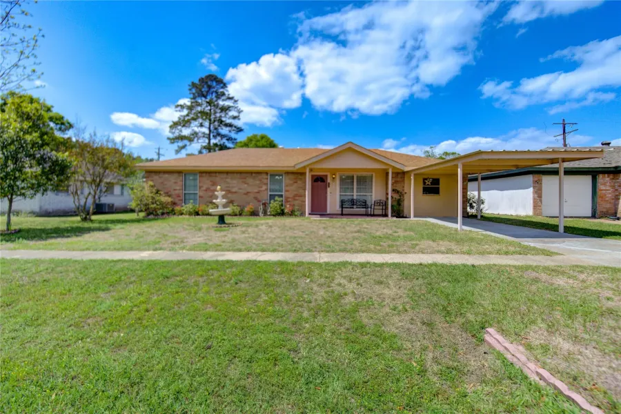 Ranch-style house with a carport, a front yard, and brick siding