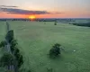 Expansive green acreage with a prominent sunset backdrop