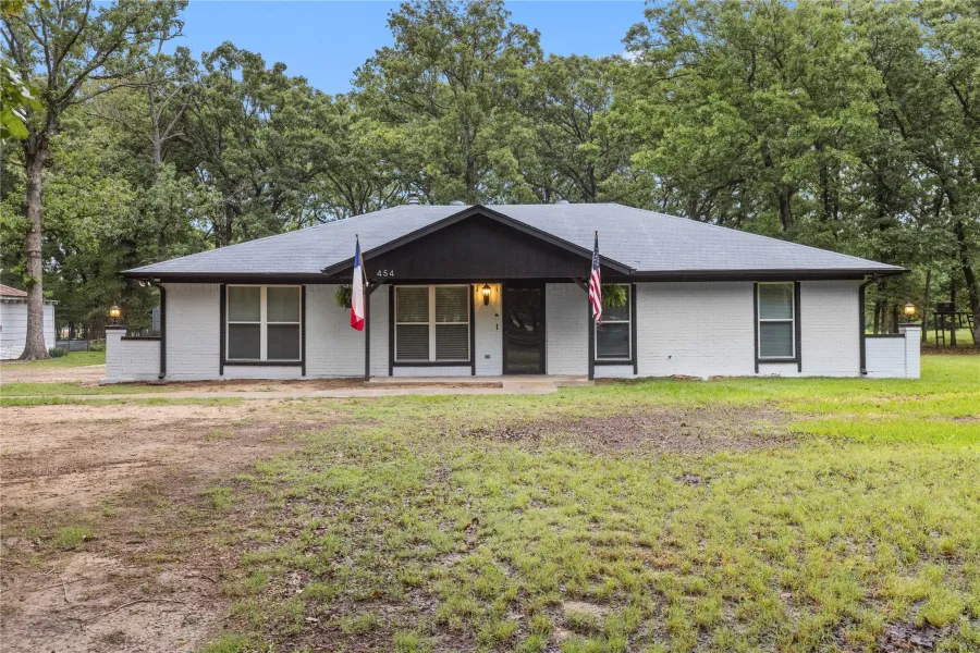Contemporary ranch-style exterior featuring white brick siding and a contrasting black roofline