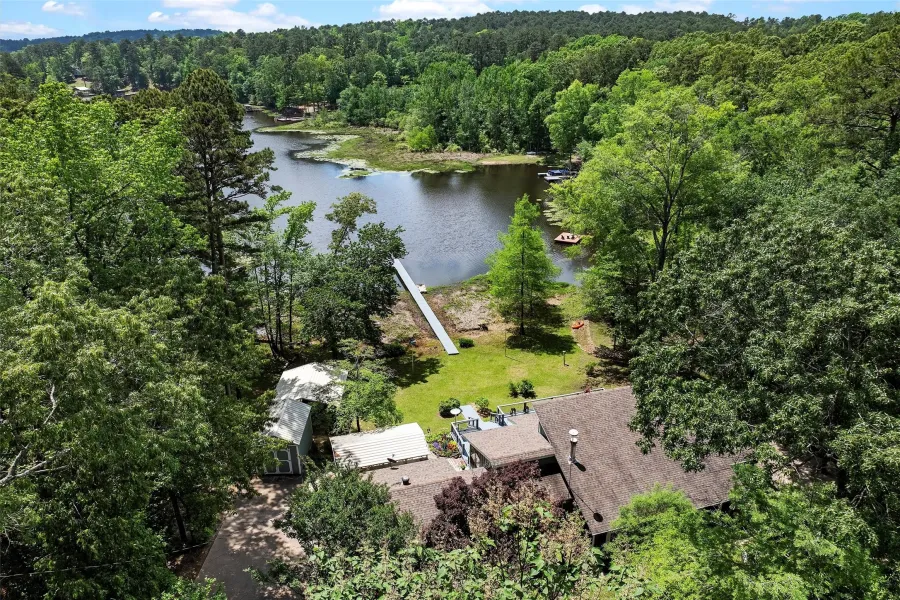 Aerial property encompassing a serene lakefront, mature tree coverage, and a private dock